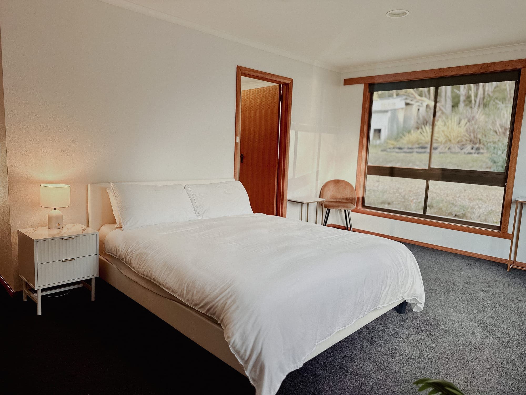 LunaStay — master bedroom with queen bed and picture windows to the bushland